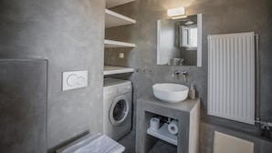 A modern bathroom with a built-in washing machine, a large sink, and a mirror above it.