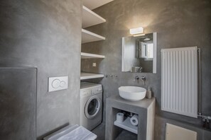 A modern bathroom with a built-in washing machine, a large sink, and a mirror above it.