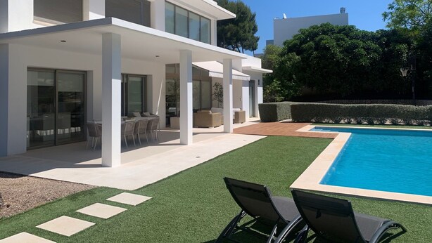 Una casa moderna con piscina, area salotto all'aperto e portico coperto.