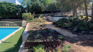 Un giardino curato con piscina, muri di sostegno in pietra e diverse piante.