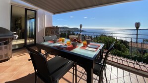 Een balkon met een ontbijtje gedekt, met uitzicht op een schilderachtig kustlandschap.