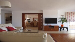 A living room with a sofa, a coffee table, a TV, and a potted plant.
