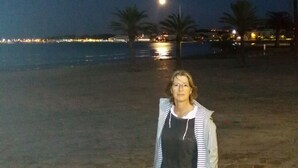 A person standing on a sandy beach at night with a moon in the sky.