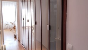 A hallway with a sliding glass door, a radiator, and a glimpse of a dining area with chairs and a table.