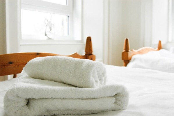 A neatly made bed with white linens and a folded white towel on top.