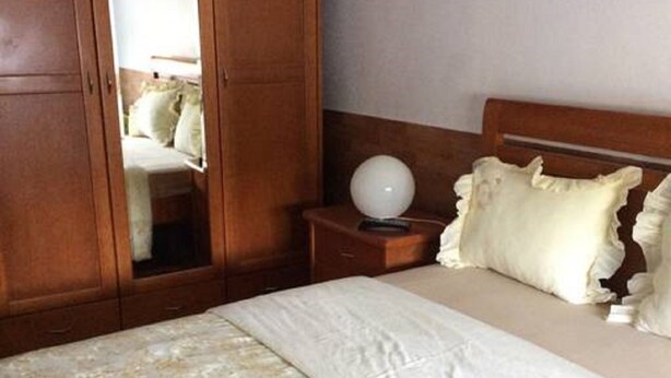 Ein Schlafzimmer mit einem großen Bett, einem Holzschrank und einem Nachttisch mit Lampe.
