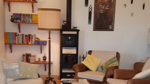 A cozy living room with a sofa, armchairs, a coffee table, a bookshelf, a fireplace, and a rug. - Apartment/ flat - Budoni (Budoni)