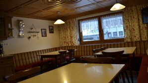 A restaurant with wooden panel ceilings, striped booths, and a large window with floral curtains.