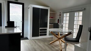 Eine moderne Küche mit weißer Arbeitsplatte, einem schwarzen Schrank und einem runden Tisch mit einem Weinglas.