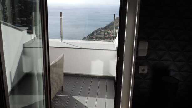Ein Balkon mit Blick auf das Meer und eine Hügelkette.