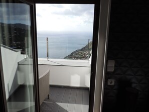 Ein Balkon mit Blick auf das Meer und eine Hügelkette.