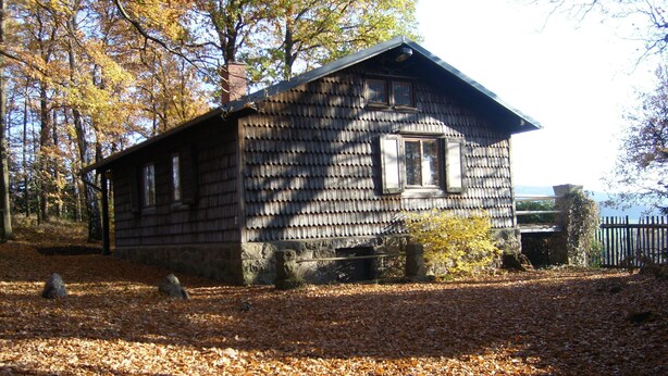 A rustic cabin with a stone foundation, wooden siding, and a chimney. - Forest, water, stone, "small Canada" in the middle of Saxony. (Kirchberg)