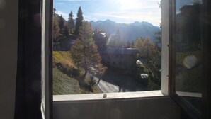 A view through a window of a mountainous landscape with buildings and trees. - Cosy refurbished 2 bedroom apartment, Sleeps 6. Close to slopes (Montvalezan)