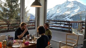 A dining area with a table set for four, overlooking a snowy mountain landscape. - Cosy refurbished 2 bedroom apartment, Sleeps 6. Close to slopes (Montvalezan)
