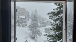 A room with a window overlooking a snowy landscape, including trees and buildings. - Cosy refurbished 2 bedroom apartment, Sleeps 6. Close to slopes (Montvalezan)