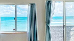 Una habitación con dos ventanas que dan a una playa.