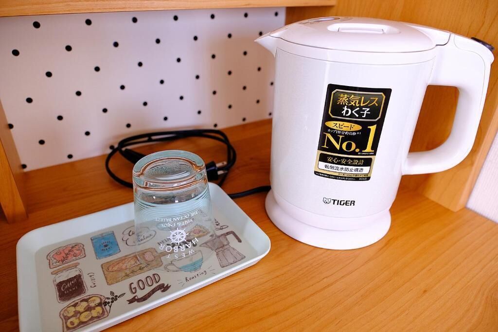 A white electric kettle with a label, a glass jar, and a plate with illustrations.