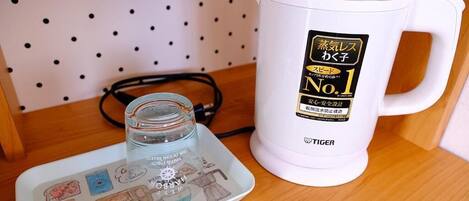 A white electric kettle with a label, a glass jar, and a plate with illustrations.