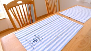 Una mesa de madera con dos individuales a rayas y dos sillas de madera.