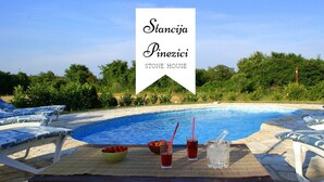 Area piscina con lettini, una ciotola di frutta e bevande.