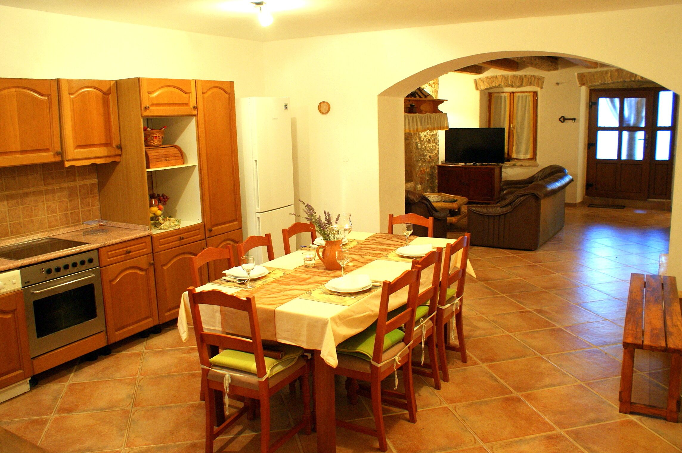 Una cocina con armarios de madera, una estufa y un comedor con mesa para cuatro.