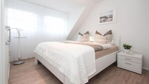 Une chambre à coucher avec un lit, une table de chevet et une lampe sur pied.