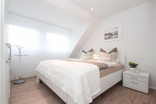 A bedroom with a bed, bedside table, and a floor lamp.