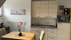Une cuisine moderne avec des meubles en bois, un four à micro-ondes et un évier. On y trouve une table à manger agrémentée d’un vase de fleurs.
