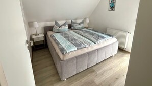 Une chambre à coucher avec un lit, des tables de chevet et un radiateur.
