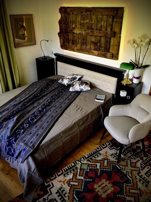 Une chambre à coucher avec un grand lit, une table de chevet, une chaise, un tapis à motifs et un panneau mural en bois.