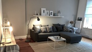 A modern living room with a grey sofa, a white coffee table, a floor lamp, and a rug.