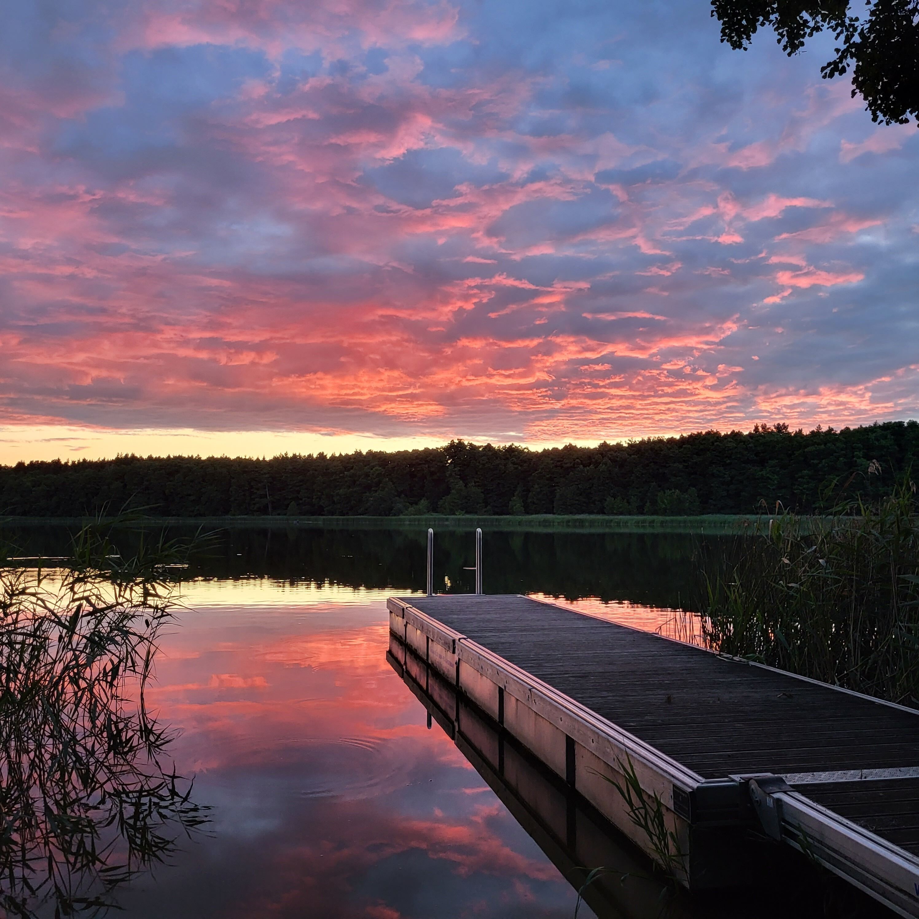 Un muelle de madera se adentra en un lago tranquilo con un cielo al atardecer.