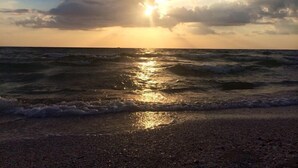 Ein Strand mit Wellen und einem Sonnenuntergang.