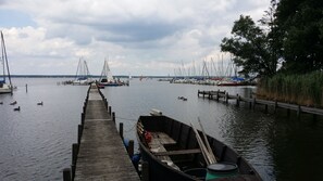 Une jetée en bois mène à une marina où plusieurs bateaux sont amarrés.