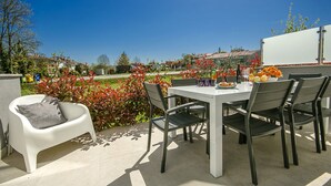An outdoor patio with a table and chairs, surrounded by plants and a clear view of the neighborhood. - PREMIUM VACATION HOME WITH SEAVIEW (Funtana)