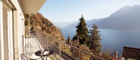 Varanda com mesa e cadeiras com vista para um lago e montanhas.