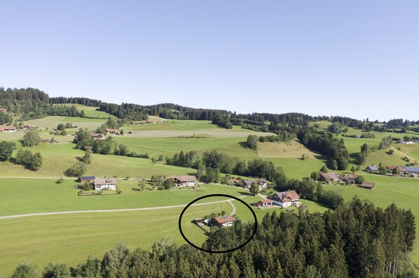 Paisaje rural con casas dispersas entre campos verdes y bosques densos.