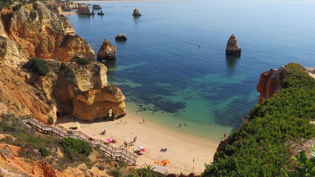 Une plage côtière aux eaux cristallines, bordée de falaises rocheuses et d’un rivage sablonneux.