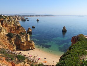 A coastal beach with clear waters, rocky cliffs, and a sandy shore. - Peaceful vacation apartment, 200 m from beach, balcony with sea view, by Lagos (Lagos)