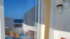 Un balcon avec une table dressée pour le petit-déjeuner, comprenant des assiettes de fraises et des verres de jus d’orange.