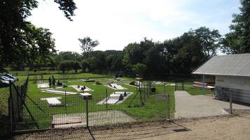 A fenced sports facility with multiple courts and a small building.