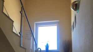 A staircase with a handrail, a window with a plant, and a wall-mounted light fixture. - Baltic Sea view from all windows, 50m to the beach (Zierow)