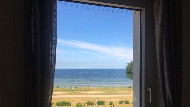 A room with a large window overlooking a beach and the sea. - Baltic Sea view from all windows, 50m to the beach (Zierow)