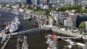 Une vue urbaine le long du littoral, avec une grande roue bien visible, un pont et divers bâtiments.