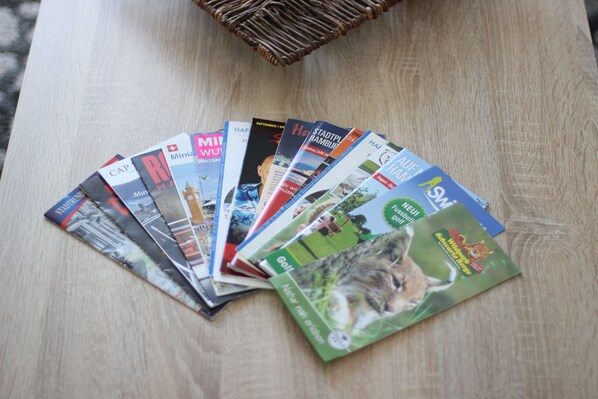A wooden table with a basket and several travel magazines.