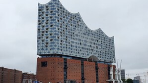 Un bâtiment moderne doté d’une façade ondulée originale, de grandes fenêtres et d’une entrée imposante.