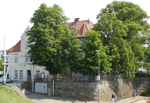 Surrounded by lush greenery, this charming building features a red-tiled roof and a white facade.