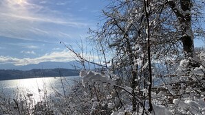 Paisagem coberta de neve com vista para um lago e montanhas ao longe.