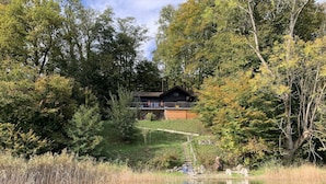 Uma cabana cercada por uma floresta densa e um lago.