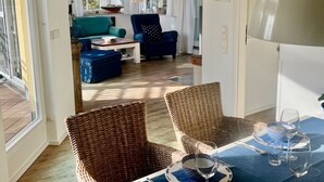 A dining area with wicker chairs, a table set with plates, glasses, and cutlery. - Comfortable penthouse apartment with 5 stars, 50 m to beach (Mecklenburg Vorpommern)